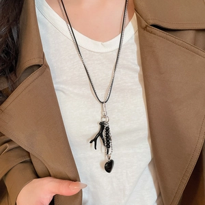 Detail of vintage double-layer necklace with black heart and branch pendant on a model