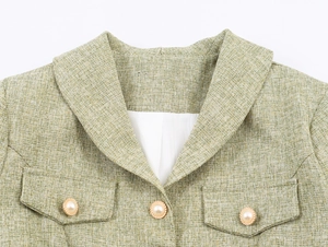 Close-up of green tweed jacket featuring large lapels and decorative gold-rimmed pearl buttons