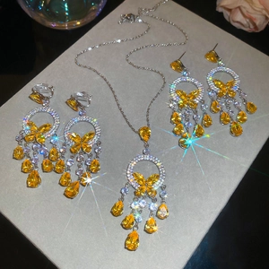 Macro detail of silver necklace and earrings set featuring yellow butterfly pendants