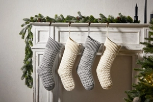 Close-up of gray and ivory knit Christmas stockings hanging on a white fireplace mantel