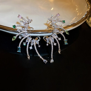 Vue détaillée de boucles d'oreilles luxe avec zircons colorés sur un plateau en porcelaine