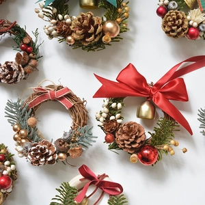 Miniature Christmas wreaths with pinecones, red berries, and bows on white background