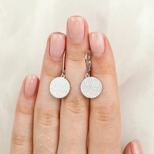Detailed view of S925 sterling silver disc earrings with pavé zircon held by hand