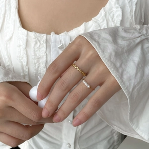 Close-up of a gold-plated chain ring and delicate pearl ring set worn on a finger