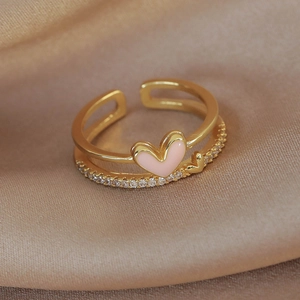 Macro shot of gold double-layered ring with pink enamel heart and shimmering cubic zirconia