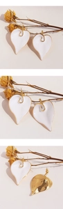 Detail of white enamel calla lily earrings with golden edges on textured floral background