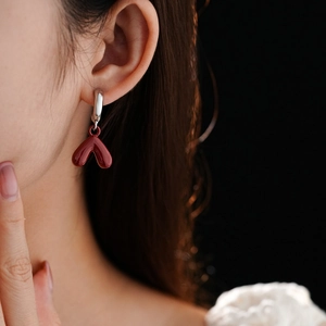Close-up of red heart earrings on a model showing the elegant drop pendant and silver clasp