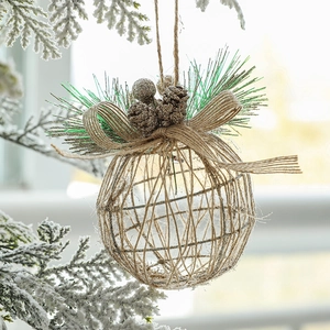 Hollow iron Christmas tree ball ornament with pine needles and red berries hanging on snow