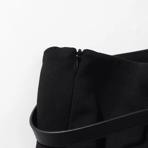Dettaglio dei pantaloni in tessuto con cerniera invisibile e cintura in pelle nera