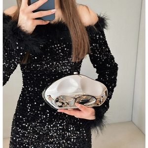 Irregular silver mirror clutch bag with wavy design held by a model in evening dress