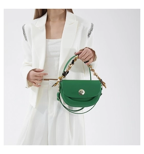 Detail of green semi-circular saddle bag with golden twist lock and silk scarf handle