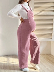 Detail of pink corduroy maternity overalls with elastic waist shown from a side view