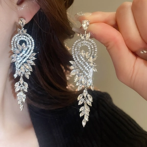 Gros plan sur des boucles d'oreilles pampilles argentées ornées de cristaux marquise et poire