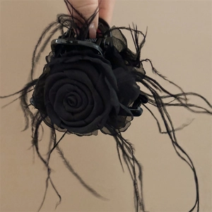 Gros plan détaillé de la pince à cheveux gothique avec rose en tissu et plumes noires