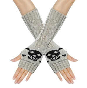Close-up of beige knit fingerless gloves featuring a black skull pattern on the back