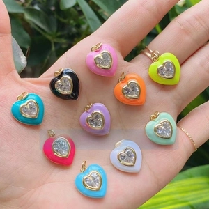 Macro shot of colorful enamel heart pendants with central cubic zirconia on a hand palm