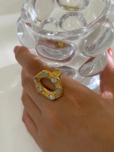 Detailed close-up of 18K gold irregular hollow ring set with white mother of pearl