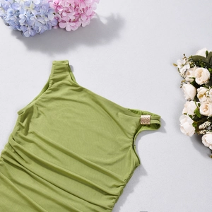 Détail du haut vert asymétrique montrant le tissu plissé et la boucle dorée