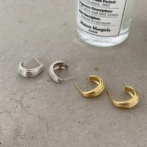 Detailed view of textured wave C-shaped earrings in gold and silver finishes