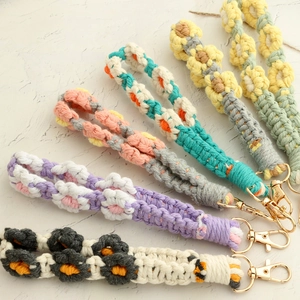 Detailed close-up of handmade woven daisy keychains with gold spring clasps