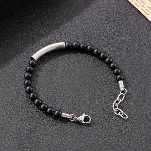 Detail of matte black onyx beads with a silver curved stainless steel bar on a beaded bracelet