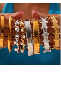 Detail of diverse 18k gold and silver titanium steel bangles featuring pearl inlay work