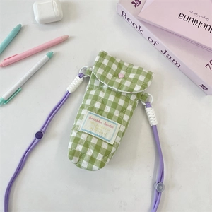 Close-up of green checkered quilted bag with heart stitching and purple strap