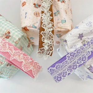 Detail of quilted canvas bags featuring lace trim handles and cute cartoon patterns