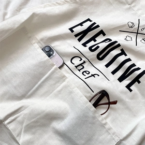 Detail of cream cotton linen apron with Executive Chef print and large front pockets