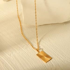Close-up of gold rectangular pendant with sunburst texture on a twisted rope chain