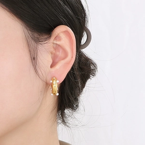 Detail of 18K gold C-shaped earrings featuring hammered texture and inlaid white pearls