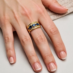 Close-up of luxury gold ring set with five blue oval sapphires and sparkling zircons