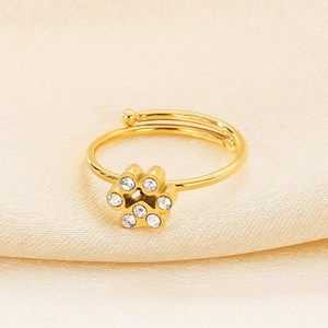 Detailed close-up of golden cat paw ring with sparkling cubic zirconia on silk fabric