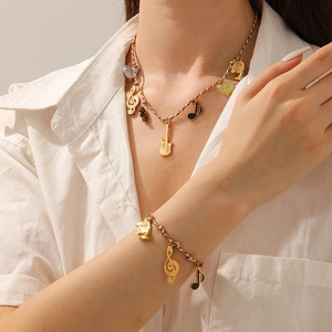 Close-up of gold-plated music theme necklace and bracelet set with guitar and note charms