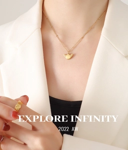 Detail of gold wing pendant necklace and quilted pattern ring on model outfit