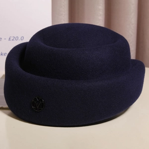 Detail of navy wool felt cloche hat featuring a metallic M logo with elegant texture