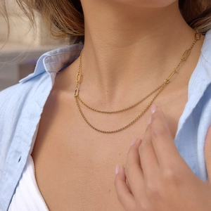 Elegante collana a doppio strato in titanio dorato con pendente geometrico sulla clavicola