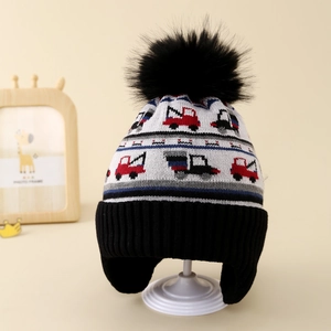 Detail of knit earflap hat for kids featuring colorful excavator patterns and faux fur pom