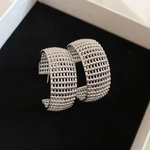 Macro view showing the silver-tone C-shape earrings with intricate micro-bead mesh texture