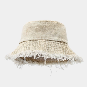 Detail of frayed edge fringe on vintage beige denim bucket hat with twill texture