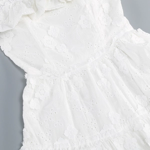 Detailed macro view of white lace embroidery and 3D floral appliques on the dress