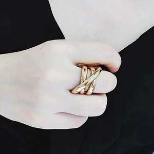 Close-up of golden multi-layer intertwined ring on finger with polished finish detail