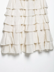 Detail of layered ruffled skirt in cream satin fabric with elegant pleated texture