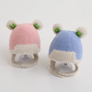 Cozy knit baby hat with earflaps, faux fur pom-poms, and cute frog patches in pink and blue