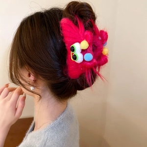 Detailed view of plush pink monster hair claw with green eyes on female hair
