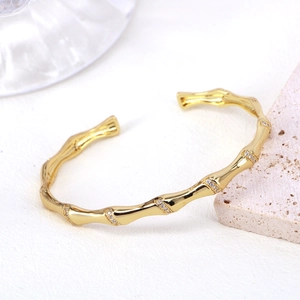 Dettaglio del bracciale rigido dorato a forma di bambù con zirconi brillanti