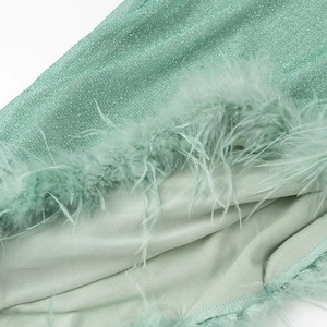 Macro shot of green glitter fabric with feather trim and inner lining on a party dress