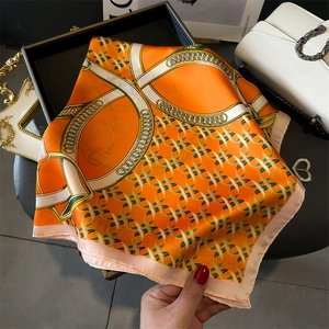 Detail of silk scarf featuring chain print patterns and contrast pink borders