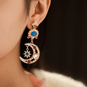 Model wearing gold sun moon and star pendant earrings with colorful enamel and pearls