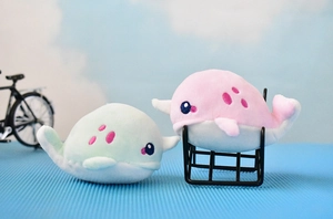 Close-up of cute pink and mint green narwhal plush toy charms as bag accessories